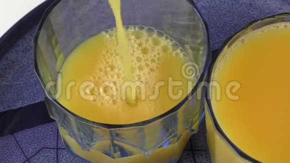 在蓝色盘子里装满橙汁的杯子里视频的预览图