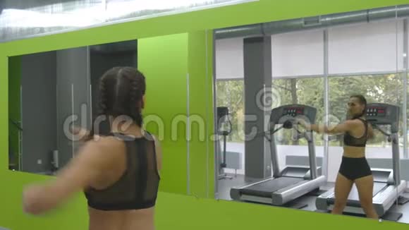 年轻的健身女子在健身房的镜子前训练女运动员在运动前伸展身体和双手视频的预览图