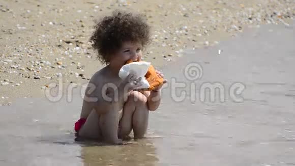 幼儿女孩在夏季海滩吃甜甜圈视频的预览图