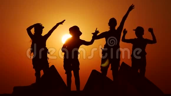 四口之家在夕阳下高兴地挥着手在沙滩上晒太阳视频的预览图