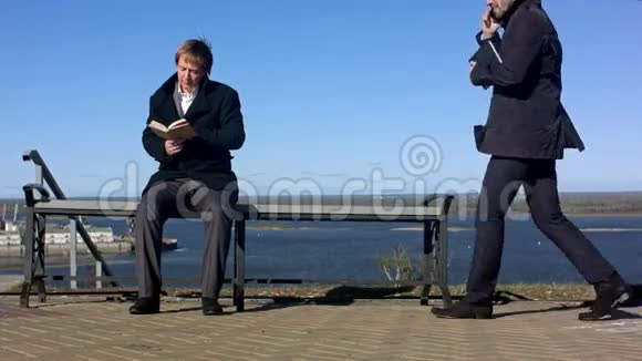两个人拿着书坐在户外的长凳上视频的预览图