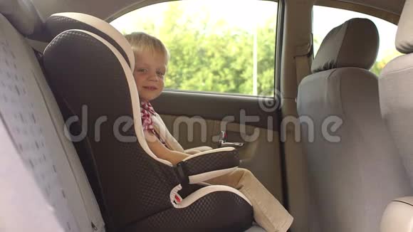 坐在汽车座位上的可爱蹒跚学步的男孩的肖像视频的预览图