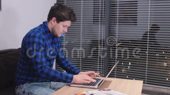 一个年轻的白种人带着笔记本电脑在桌子上工作视频的预览图