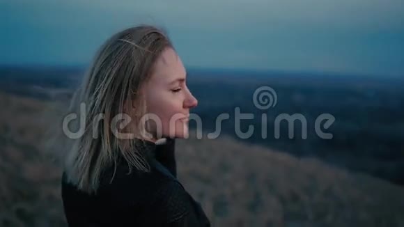 美丽的女孩看着夕阳和微笑头发在风中视频的预览图