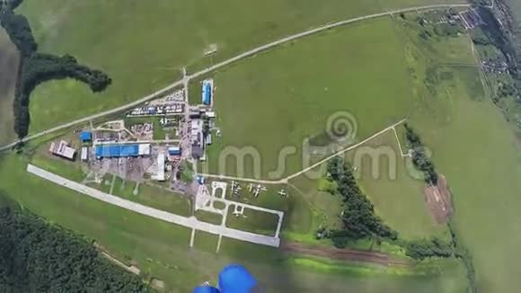 跳伞女孩跳伞在绿色的田野和森林上空极限运动视频的预览图