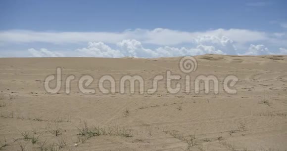 巨大的白色蓬松云团在沙漠沙丘上翻滚视频的预览图
