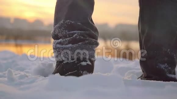 在冬天寒冷的雪天里徒步旅行的人的腿走过自然多彩的晚霞伴着美丽的天空视频的预览图