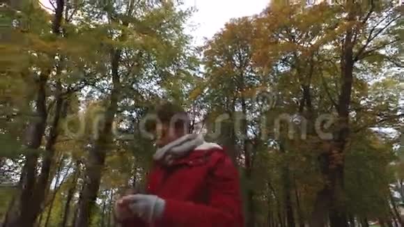 带智能手机的年轻人在秋天公园散步视频的预览图