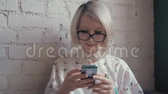 快乐的年轻美女在咖啡馆里喝着咖啡在智能手机上发短信视频的预览图