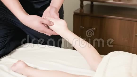 男性理疗师按摩师为躺在按摩床上的小孩做一个疗愈性放松的足部按摩视频的预览图
