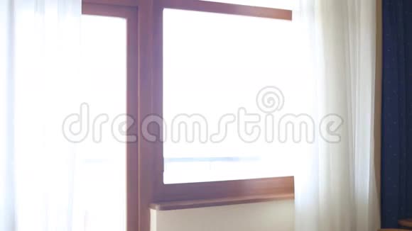 美女打开大窗户上的窗帘让光线进入房间看着窗外视频的预览图