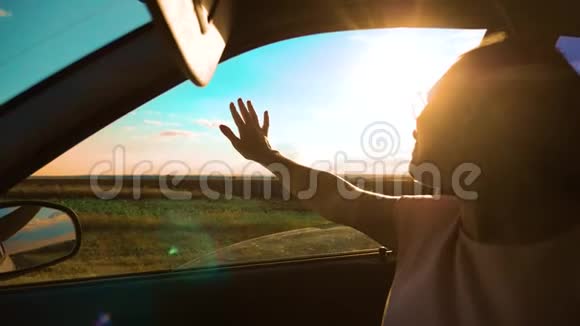 女孩挥手在窗户阳光下风在汽车慢动作视频年轻快乐的女孩开汽车视频的预览图