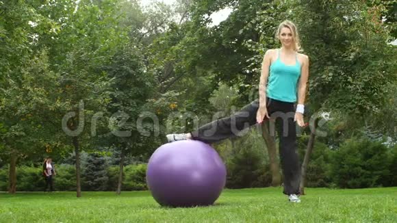 在公园里一个年轻的女人坐在绳子上带着一个球视频的预览图