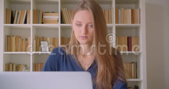 年轻有魅力的高加索女商人用笔记本电脑在办公室室内观看照相机的特写照片视频的预览图