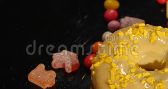 4K镜头的釉甜甜圈与洒旋转与正常速度隔离在黑色背景视频的预览图