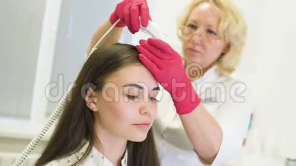 皮肤科医生诊断一个年轻漂亮女孩的头发结构与一个特殊的工具一个旋毛镜视频的预览图