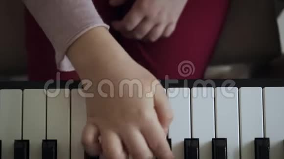 在电动钢琴上演奏的小女孩手上的俯视图视频的预览图