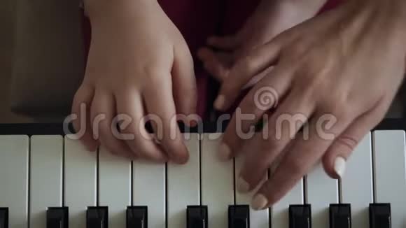 在电动钢琴上演奏的小女孩手上的俯视图视频的预览图