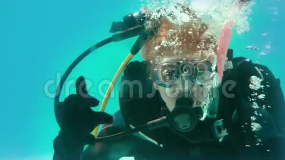 戴着潜水装备的女人看着摄像机在水下制作OK标志视频的预览图