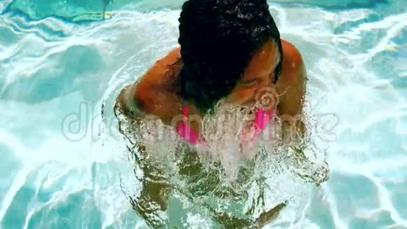 穿着粉红色比基尼的快乐女人在游泳池里抖湿头发视频的预览图