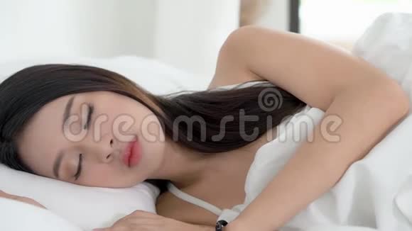 美丽的亚洲年轻女子躺在床上头靠在枕头上舒适而快乐地移动着全景相机视频的预览图