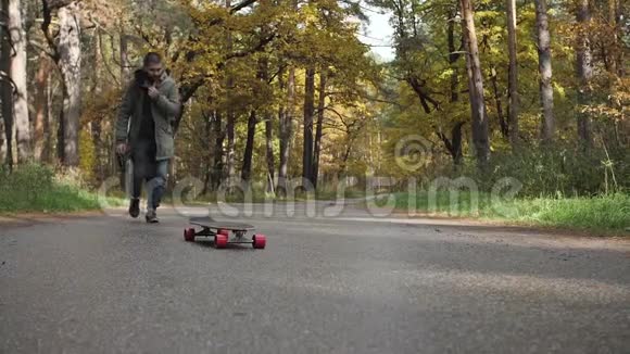 一个人骑着长板溜冰在穿过森林的道路上视频的预览图