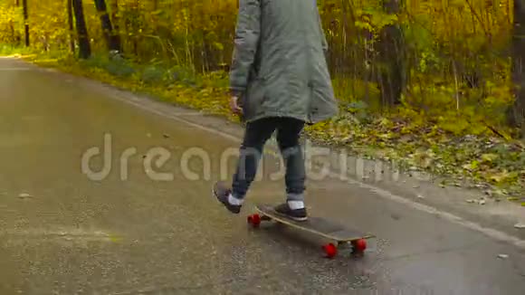 一个人骑着长板溜冰在穿过森林的道路上视频的预览图