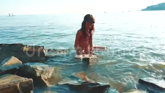 小女孩用石头和石头在海里洗澡少女女儿在海浪中畅游生活方式视频的预览图