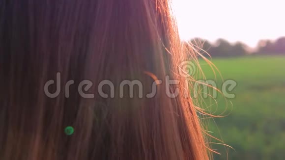 田野里年轻漂亮的女孩看着夕阳近距离射击慢动作视频的预览图