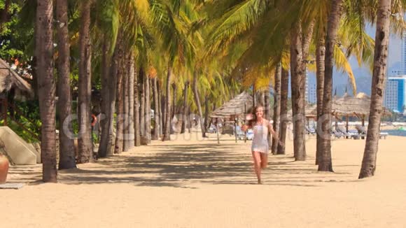 金发女孩在沙滩上的棕榈树之间奔跑视频的预览图
