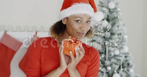 戴着圣诞帽的漂亮女人拿着礼物视频的预览图