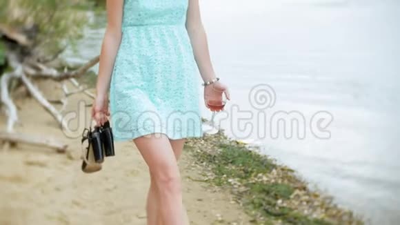 年轻的美女喝着酒杯里的酒沿着海边的沙滩散步视频的预览图