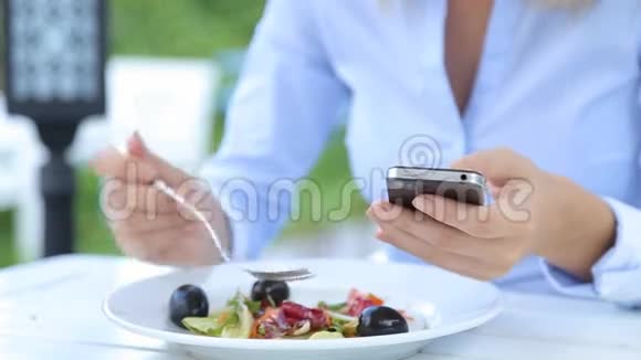 美丽的女人使用智能手机在城市咖啡馆吃沙拉视频的预览图