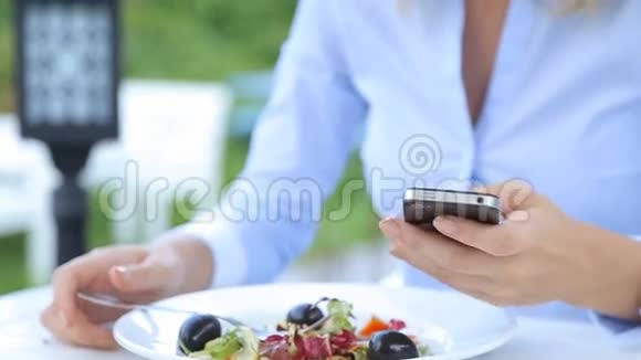 美丽的女人使用智能手机在城市咖啡馆吃沙拉视频的预览图