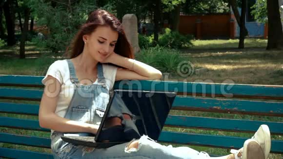 有魅力的女孩坐在有笔记本电脑的长凳上视频的预览图