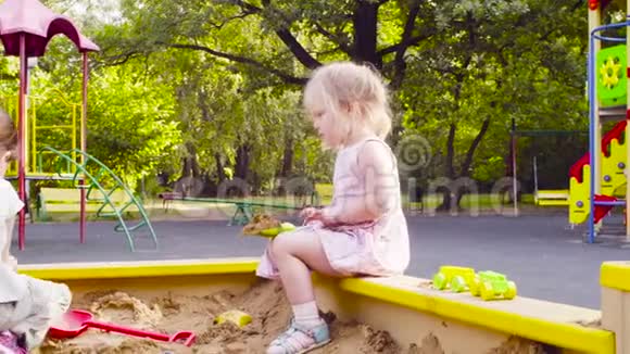 一个坐在沙箱里的小女孩正在捡沙子视频的预览图
