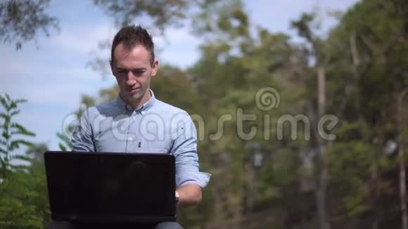 在公园里玩电脑的年轻帅哥视频的预览图