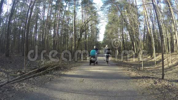 一对幸福的家庭夫妇驾着婴儿车在春天的森林里散步4公里视频的预览图