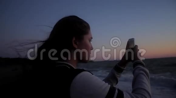 女孩在海滩上拍照手持射击视频的预览图