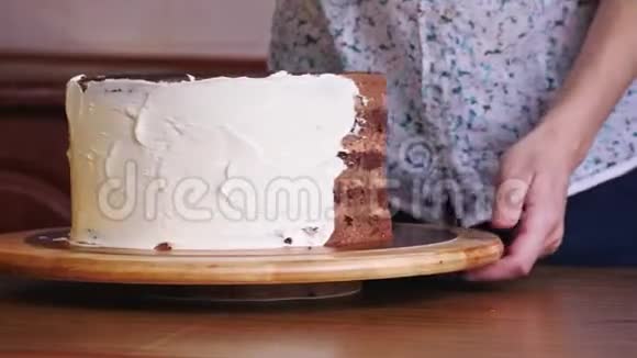 用抹刀将奶油粘在海绵蛋糕上的女人手的特写视频的预览图