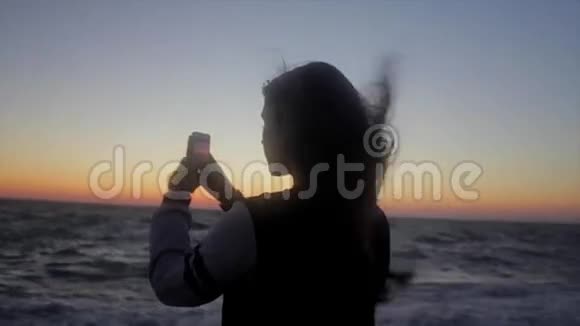 女孩在海滩上拍照手持射击视频的预览图
