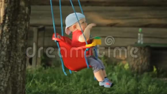 可爱的小男孩在夏天的花园里玩秋千树上挂着一圈圈视频的预览图