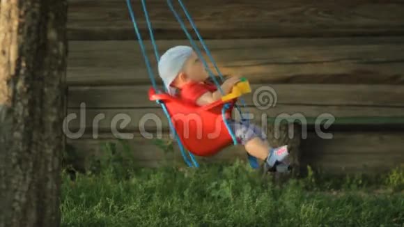 可爱的小男孩在夏天的花园里玩秋千树上挂着一圈圈视频的预览图