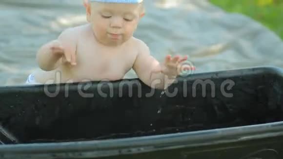 小男孩坐在绿色花园的盆地附近美丽的宝宝微笑着打着水涨船高视频的预览图