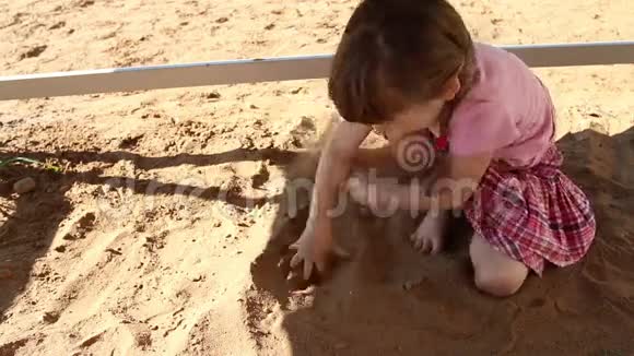 快乐的粉红色小女孩在夏天的操场上玩沙子视频的预览图