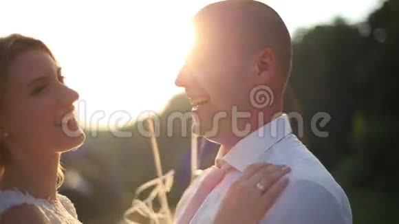 结婚那天年轻夫妇拥抱的温柔时刻日落时分新娘和新郎在桥上放气球视频的预览图