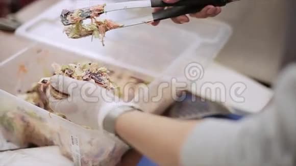 戴手套的人把准备好的蔬菜沙拉放在烤面包上做汉堡包快餐露天活动视频的预览图