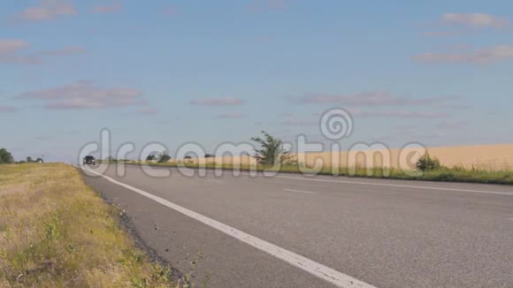 这辆车行驶在Pshenichnyh田野之间的乡村公路上日落时分在麦田的背景下视频的预览图