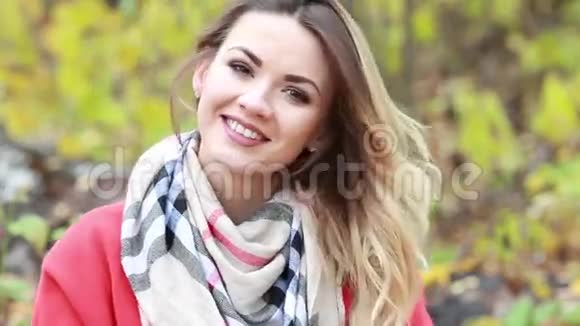 秋天公园的一位穿红色外套的漂亮年轻女子视频的预览图