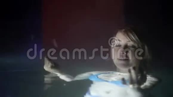 穿着蓝色比基尼的年轻女子晚上在室外游泳池里捕捉雪花视频的预览图